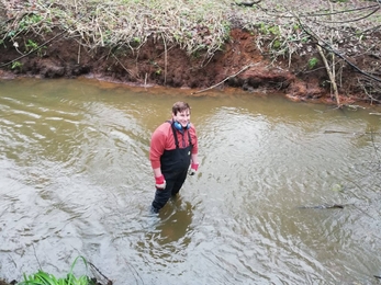 Joshua stands in a river 