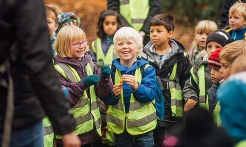 School children visiting a nature reserves, holding leaves