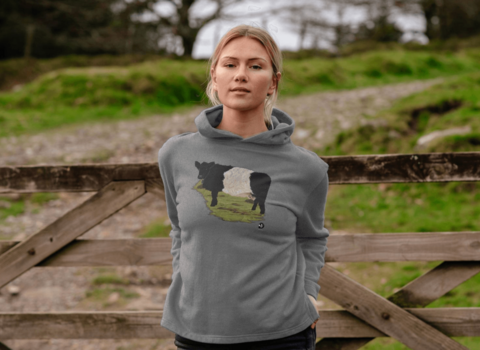 A young woman wearing a hoodie with a Belted Galloway design
