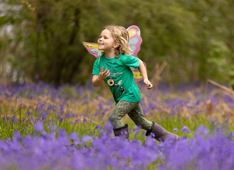 Girl running through bluebell wood
