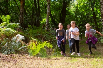 A group of young girls running through the woods
