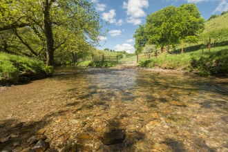 Clear river with green grassy hills