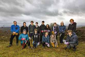 Young people gathered in a group with conservation tools e.g. saws, loppers