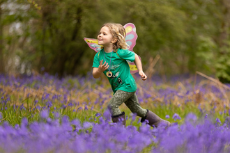 Girl running through bluebell wood