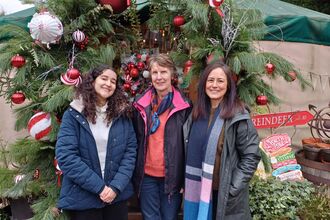 Three office-based volunteers stood in front of festive decorations
