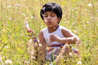 Girl with magnifying glass in meadow