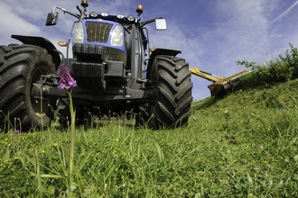 Tractor clearing hedge