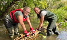 Volunteers creating n artificial river berm from woven branches