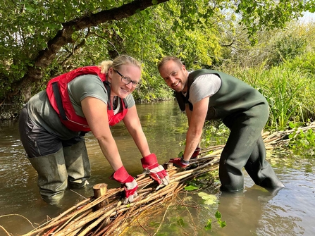 Volunteers creating n artificial river berm from woven branches