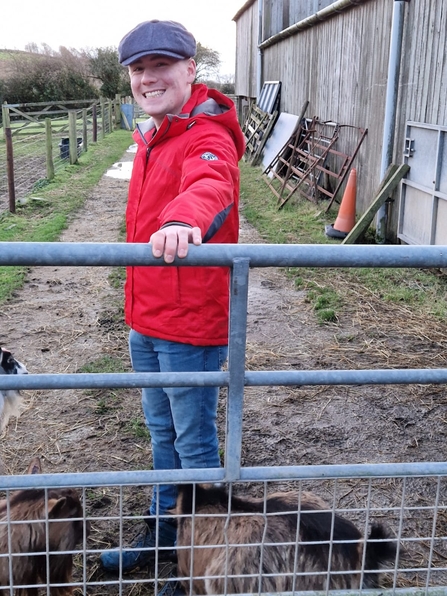 Young person stood in front of a gate and smiling