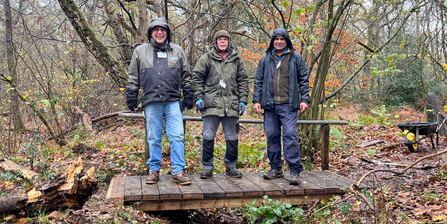 Volunteers and staff stood on top of a new wooden bridge 