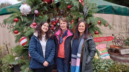 Three office-based volunteers stood in front of festive decorations