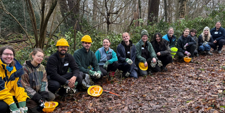 A line of young volunteers crouching on the floor with helmets and tools during a youth action volunteer day