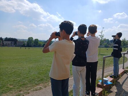A group of young people looking through binoculars