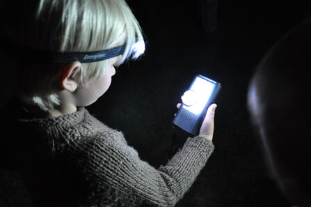 A child using a bat detector at night 