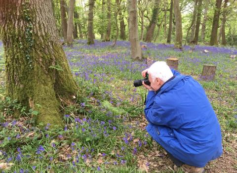 Man taking photo of bluebells on photography course