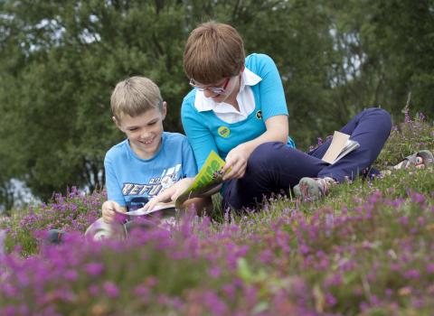 Child reading Wildlife Watch magazine with mother