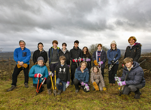 Young people gathered in a group with conservation tools e.g. saws, loppers