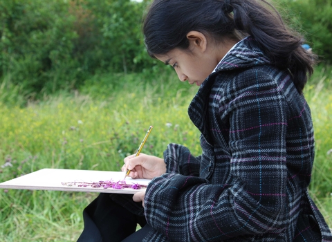 A child studying flowers with a clipboard